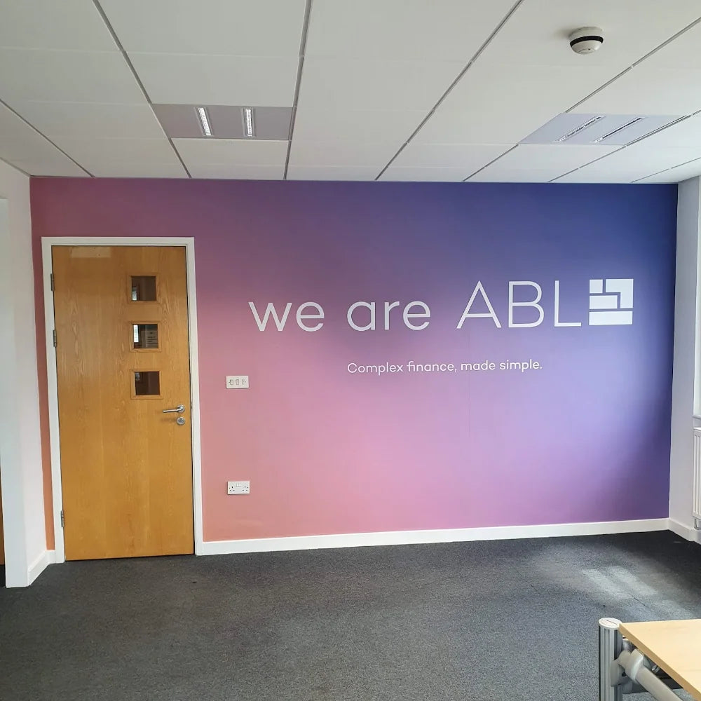 A printed wall logo showing a full wall covered in a wrap with white text showcasing a companies brand corporate logo
