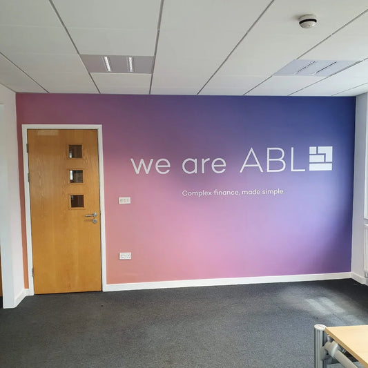 A printed wall logo showing a full wall covered in a wrap with white text showcasing a companies brand corporate logo