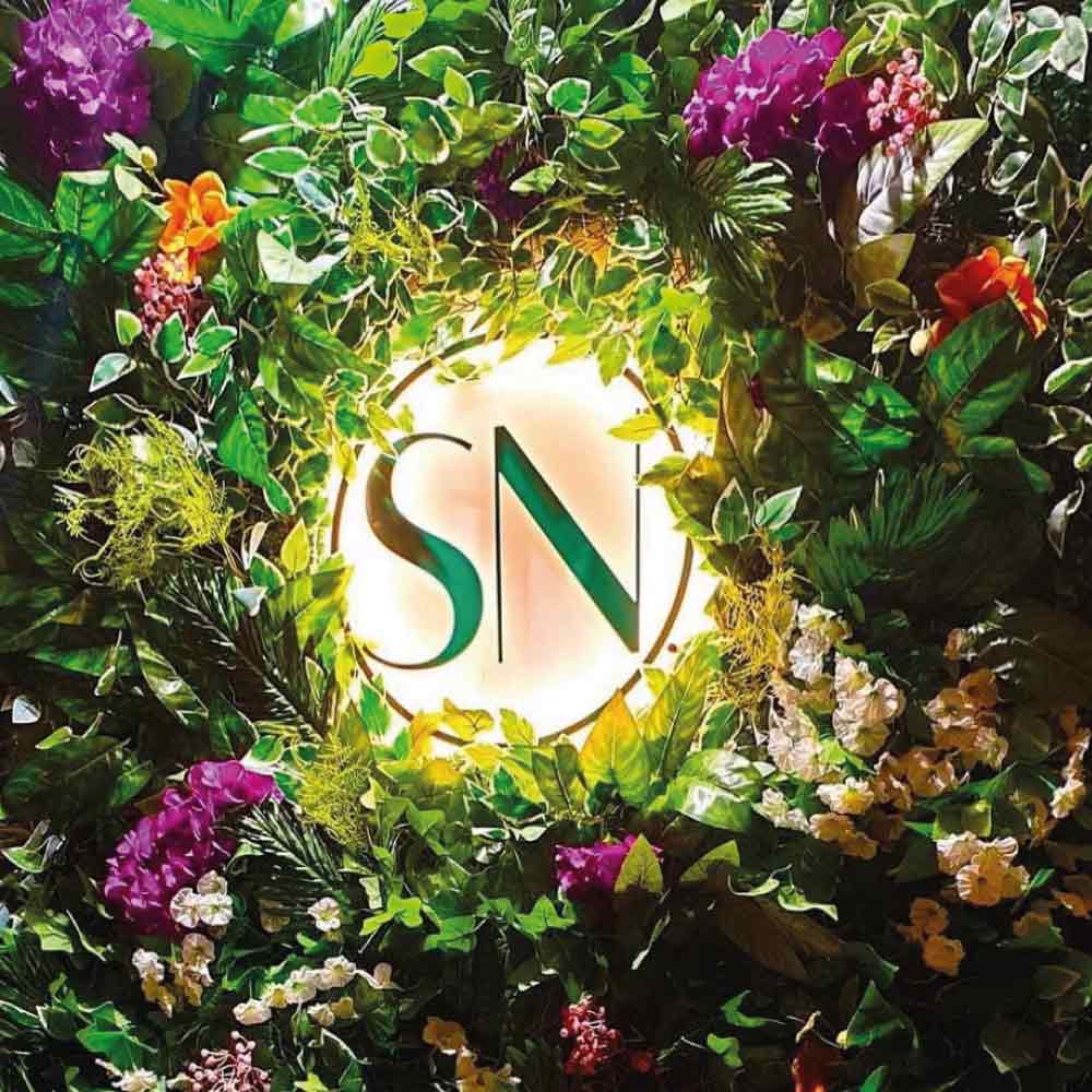 example of a circel acrylic salon sign with warm white illumination and SN cut out in green