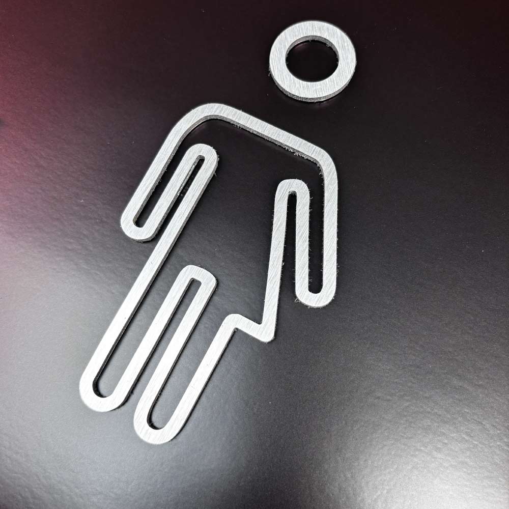 Gender neutral toilet door signs on a dark wall showing a brushed Silver Aluminium icon