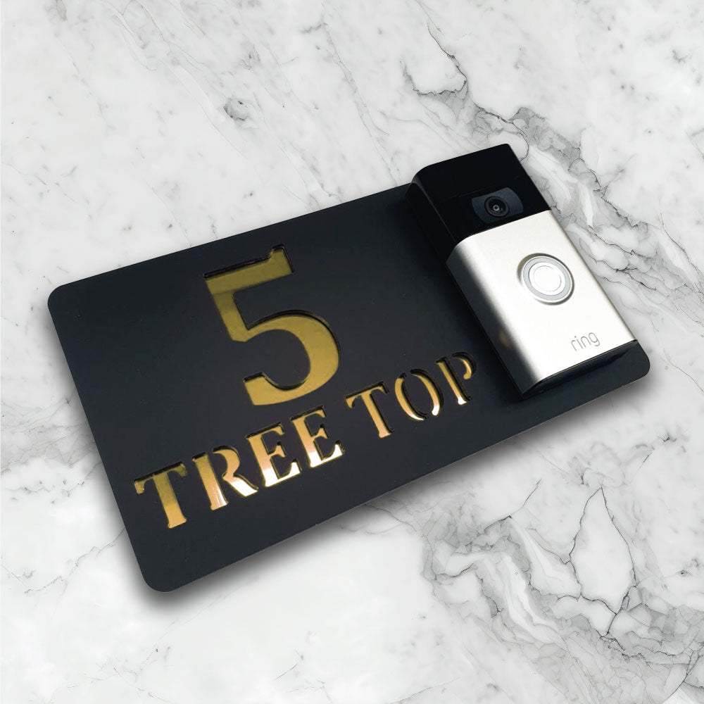 Black house sign with a video doorbell on showing text and street address in a black and gold finish side
