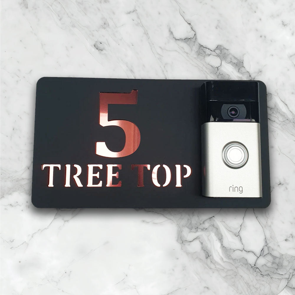 Black house sign with a video doorbell on showing text and street address in a black and rose gold face on finish