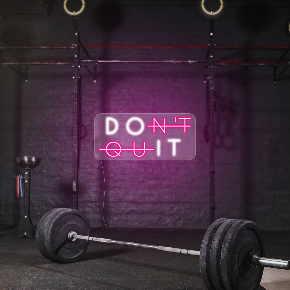 dont quit in a pink and white lights on a dark gym wall 