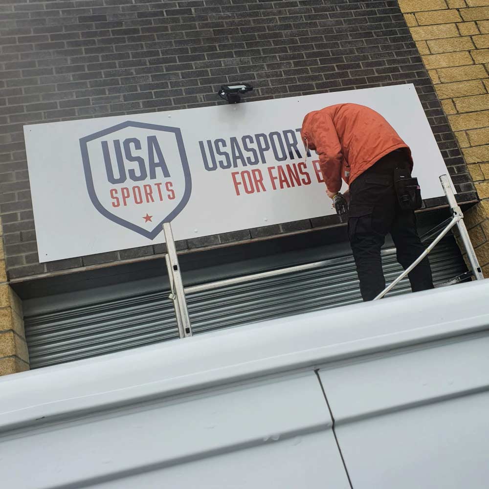 man on a scaffold tower fitting a sign