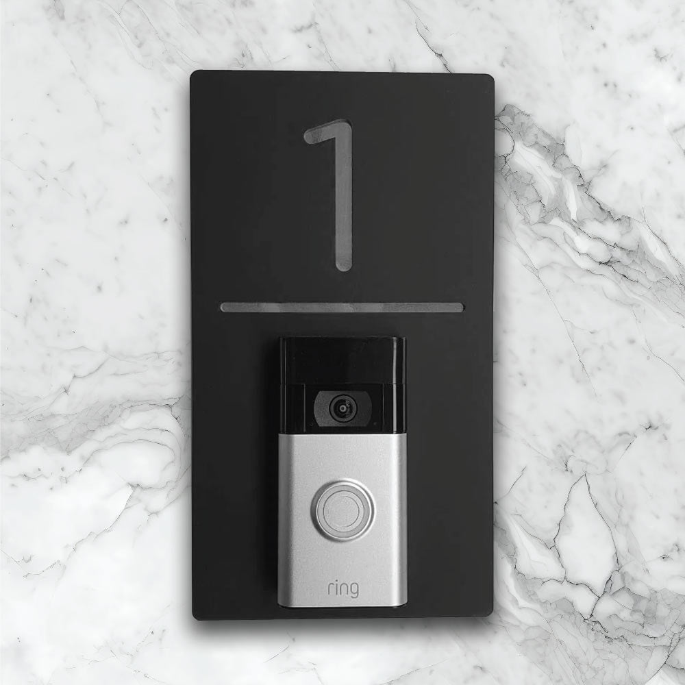 Black verticla house sign with silver details with an added video ring doorbell on face of house sign